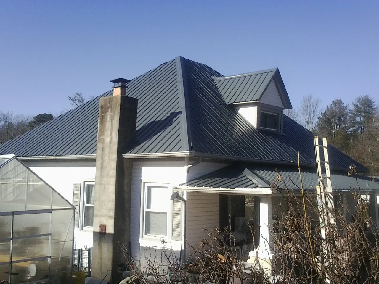 Dark blue standing seam metal roof on a white farmhouse with dormer — Slate & Tile Roof Repair by Roofing Brothers in Mohegan Lake