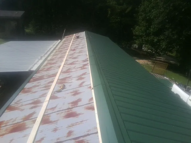 Old rusted panels beside newly installed green metal roofing — Wind Damage Roof Repair by Roofing Brothers in Mohegan Lake