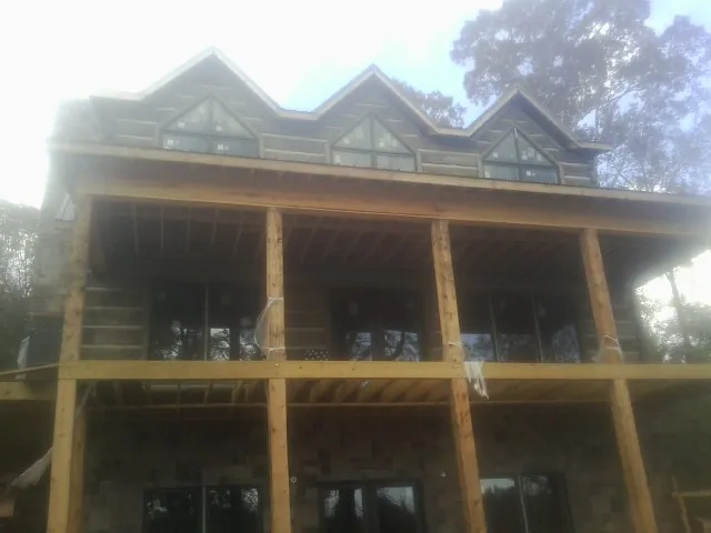 Dormers and porch framing on a large log home under construction — Roof Coating work by our crew in Mohegan Lake