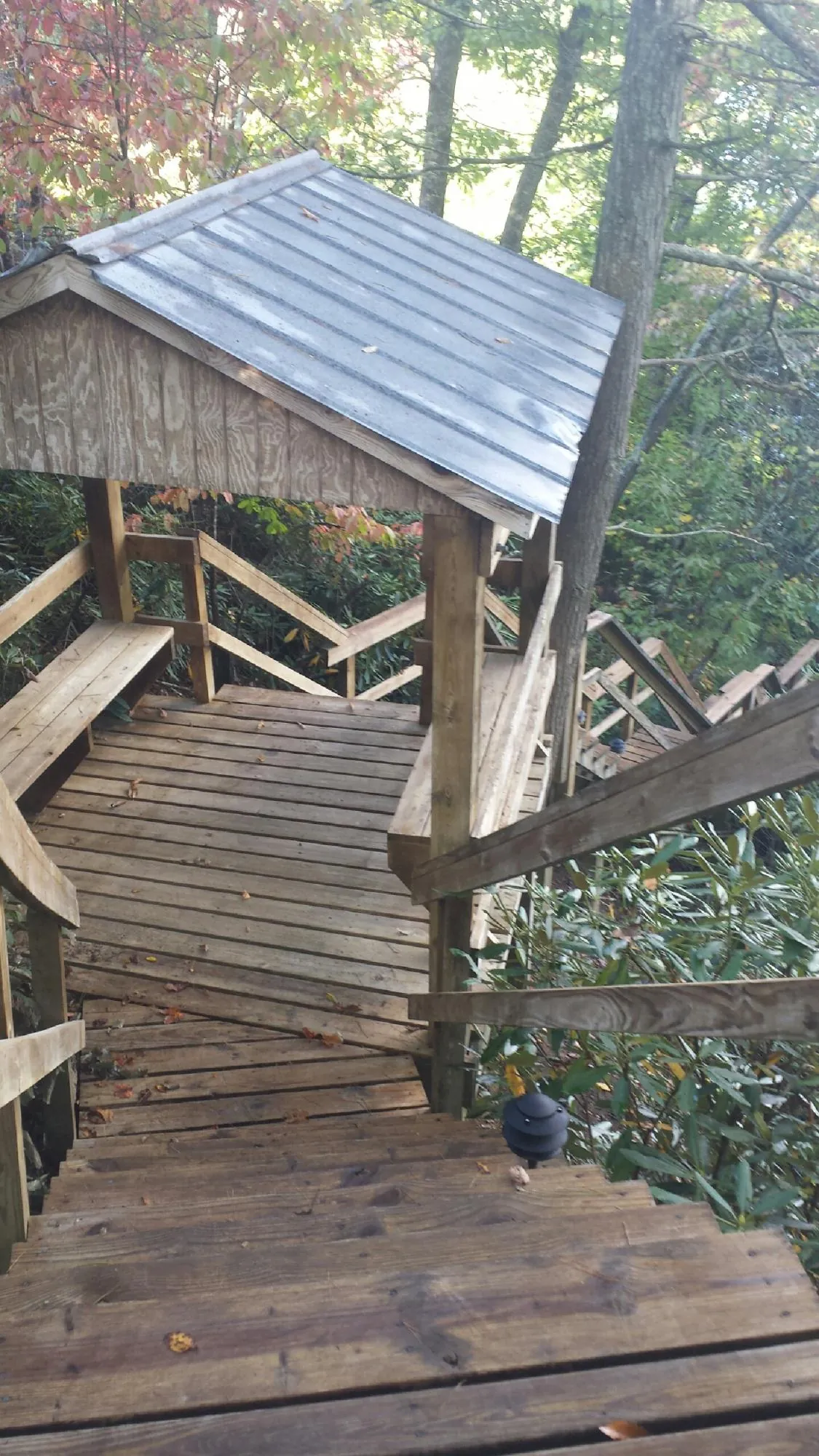 Metal roofed shelter over wooden steps on a wooded walkway — Skylight Repair & Installation work by our crew in Mohegan Lake