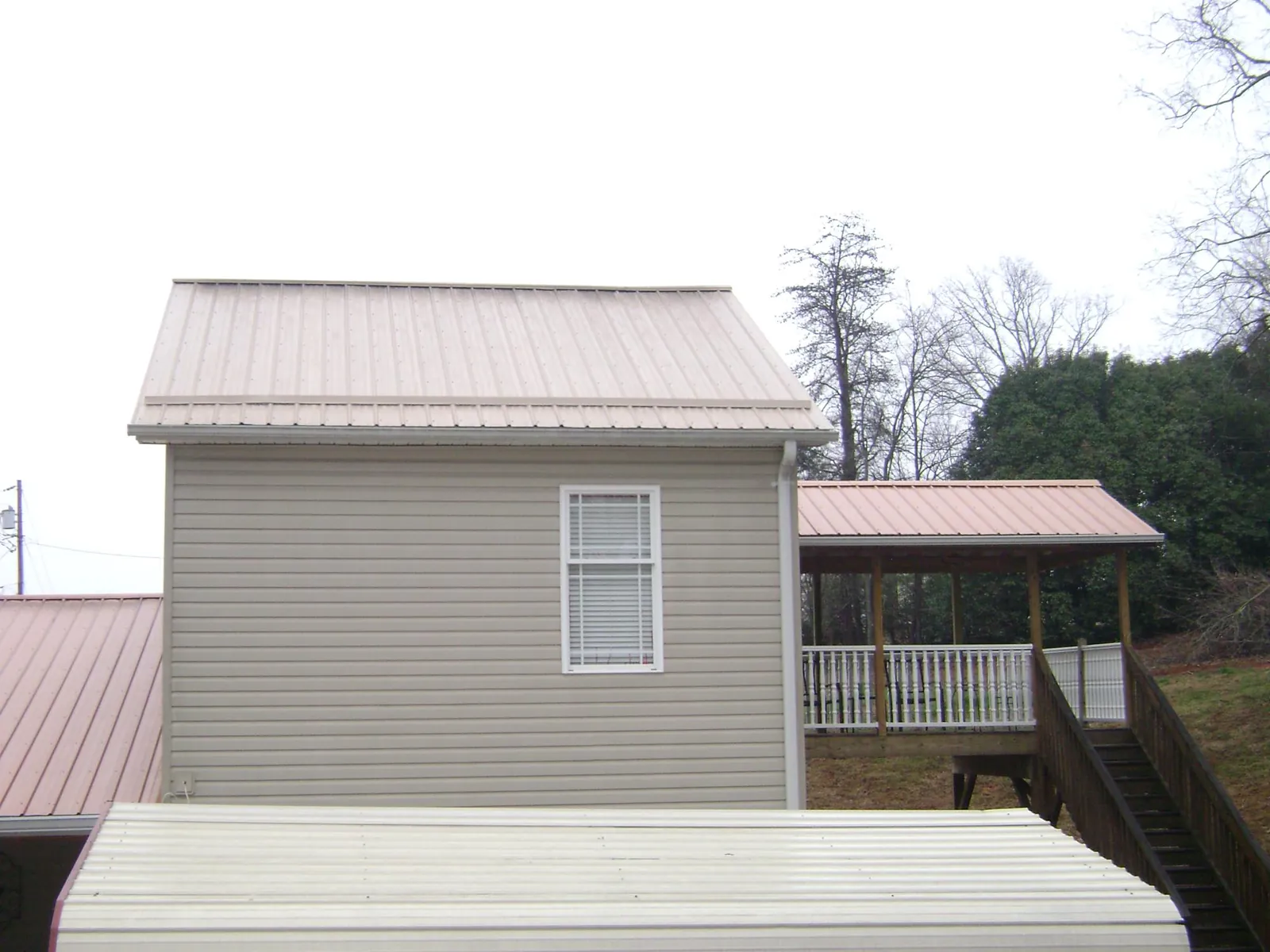 Tan metal roofs on a two story addition and attached porch, from a Roof Replacement job in Mohegan Lake