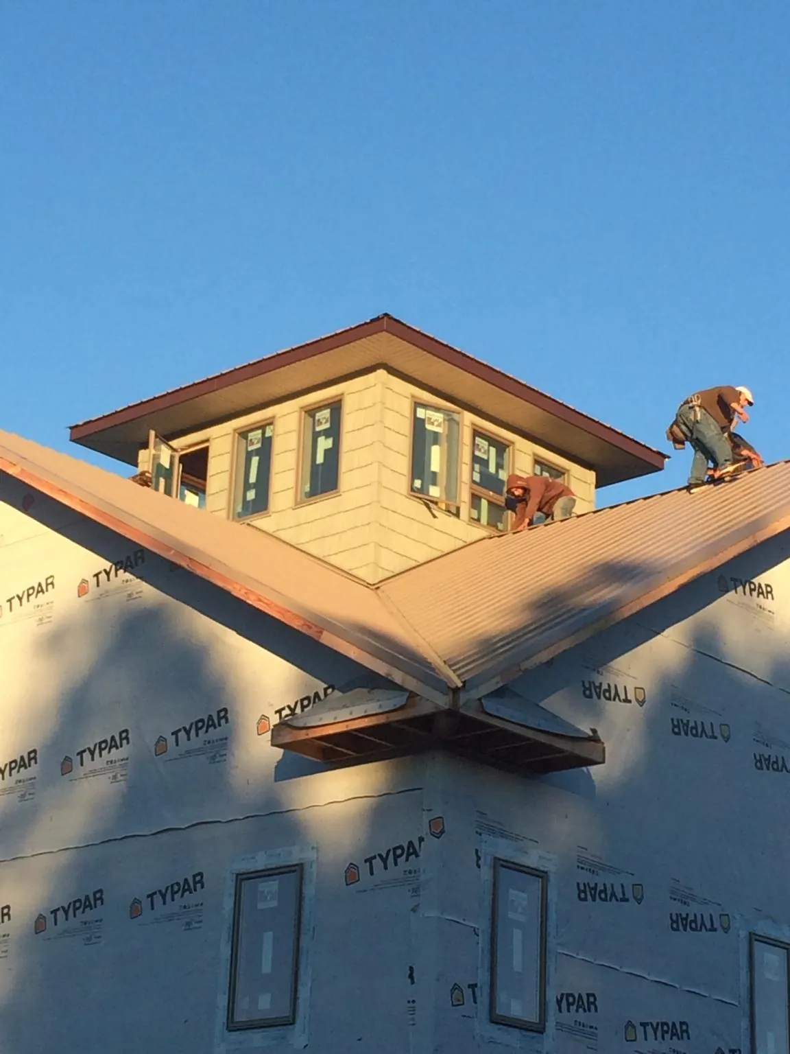 Roofers working around a rooftop cupola on a new metal roof at sunset — Roof Waterproofing in Mohegan Lake by Roofing Brothers